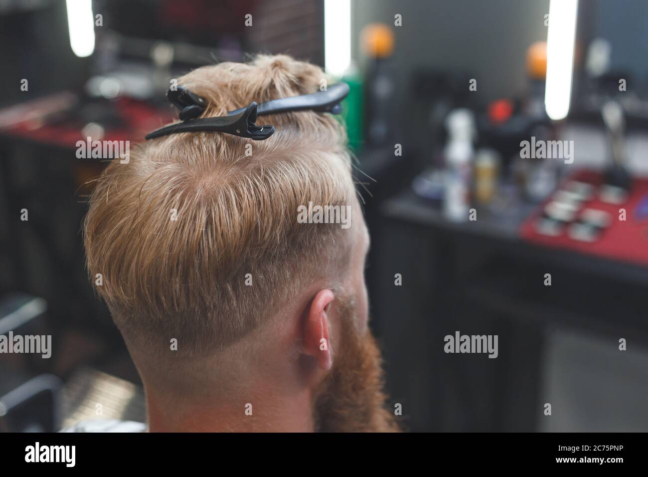 Hairdressing services. Hair styling process in a barbershop. Hair clip with a hairpin while cutting Stock Photo