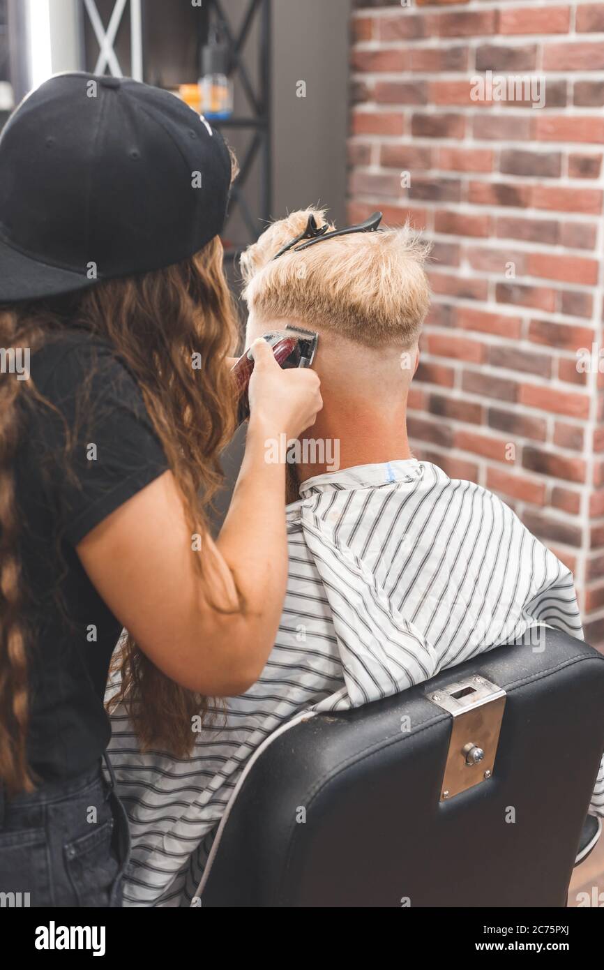 Men's haircut in a barbershop. Hair care. Barber in mask protecting from virus. Haircut in quarantine. Stock Photo