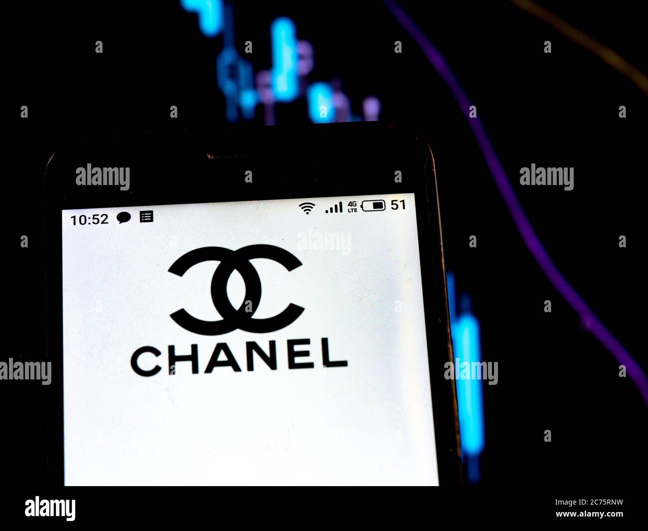 In this photo illustration Chanel logo is seen displayed on a smartphone on the background of a graph with falling curves. According to international media reports during the coronavirus epidemic COVID-2019 Chanel is discontinued. Stock Photo