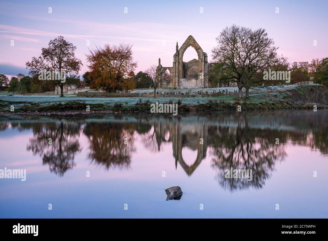 The ruins of Bolton Abbey in Wharfedale, Yorkshire, are reflected in the River Wharfe on a beautifully calm, frosty autumn morning. Stock Photo