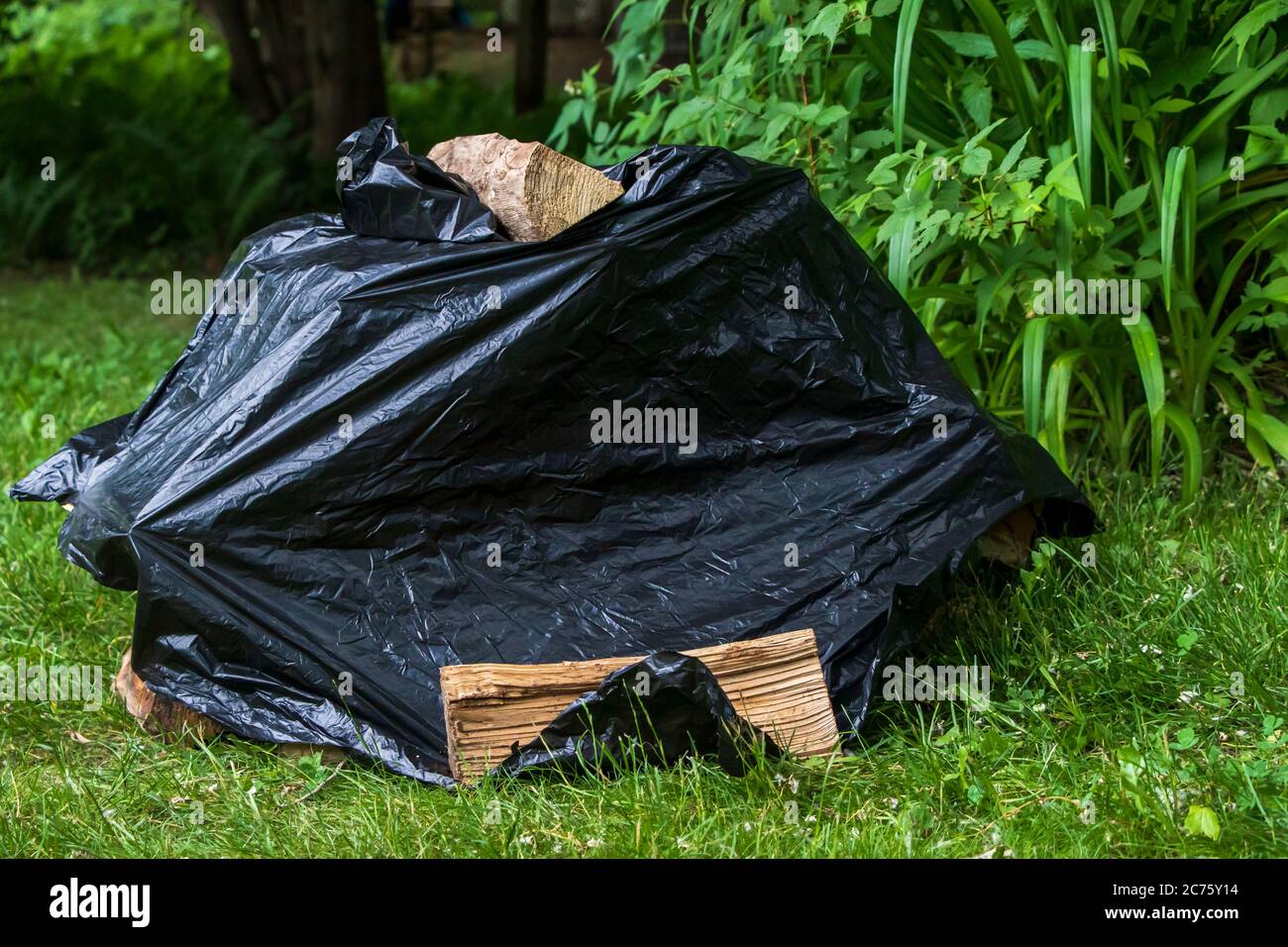 Stacked campfire logs cover by garbage plastic bag Stock Photo