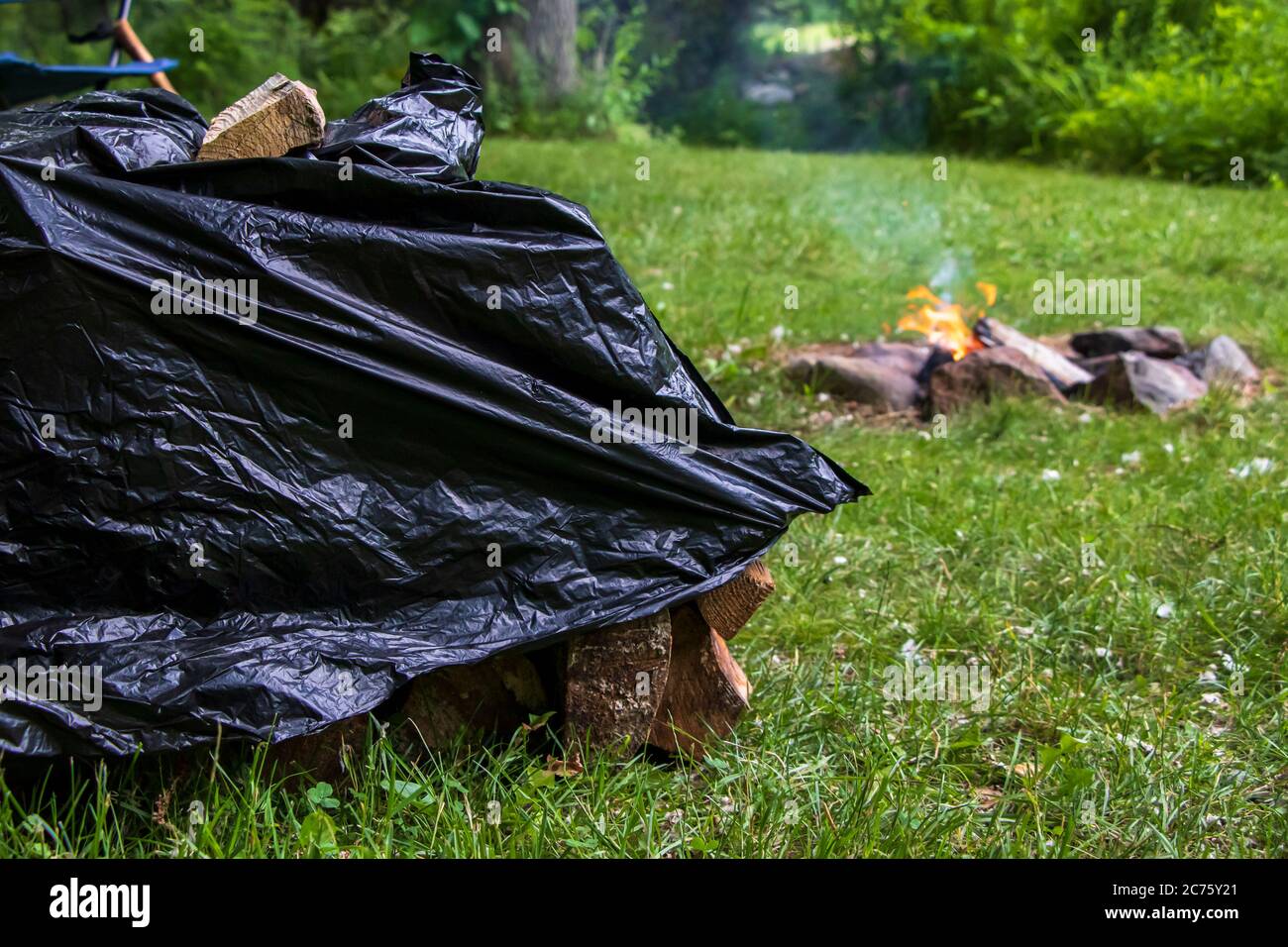 Stacked campfire logs cover by garbage plastic bag Stock Photo