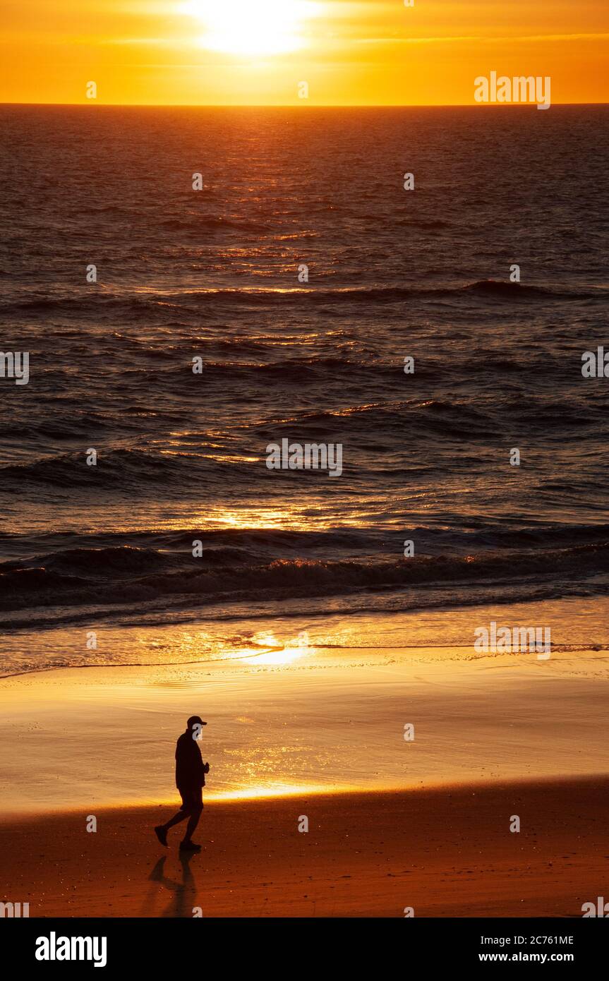 Silhouette of man jogging on a beach during a colorful sunrise Stock ...