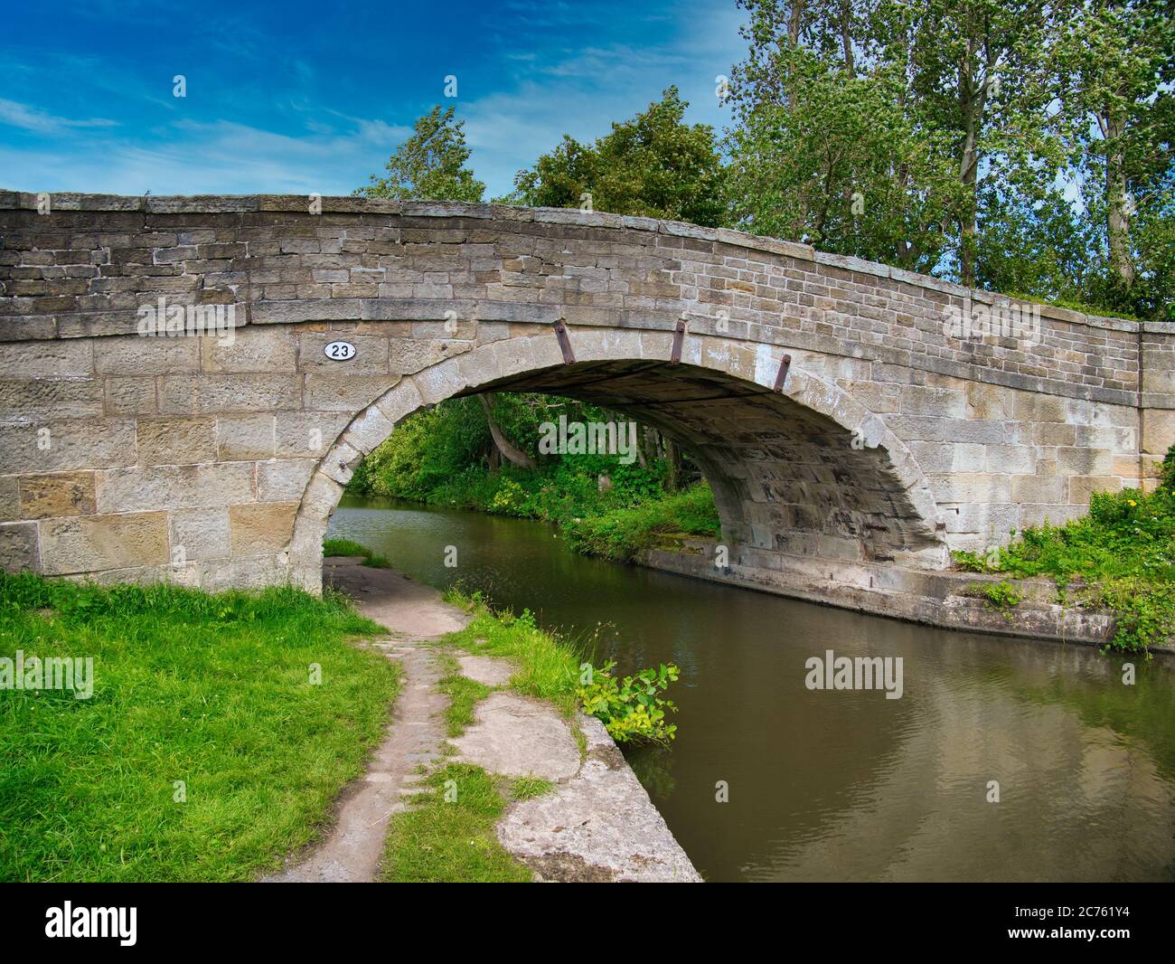 Sandstone Bridge 23 on a quiet, rural section of the Leeds to Liverpool Canal in Lancashire, UK. Taken on a sunny day with blue sky Stock Photo