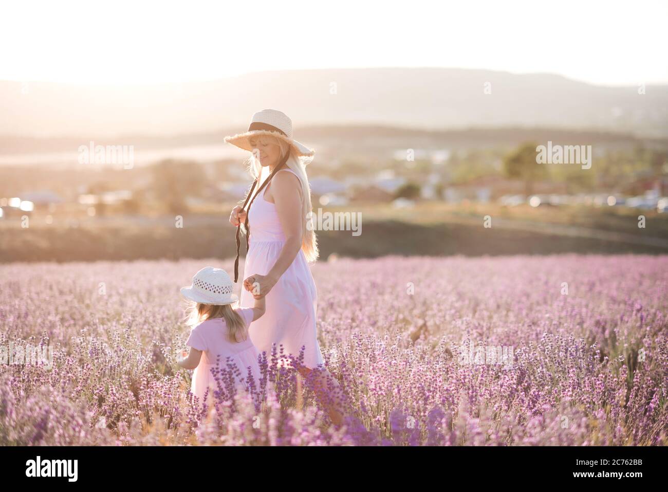 Smiling young mother walking with baby daughter 12 year old in
