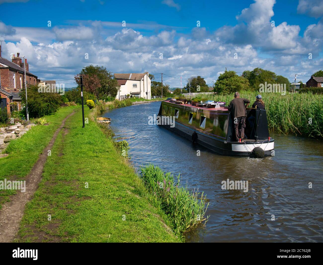 Holidaymakers on a narrowboat cruising on the Leeds to Liverpool Canal in tranquil, rural Lancashire. Taken on a sunny day in summer. Stock Photo