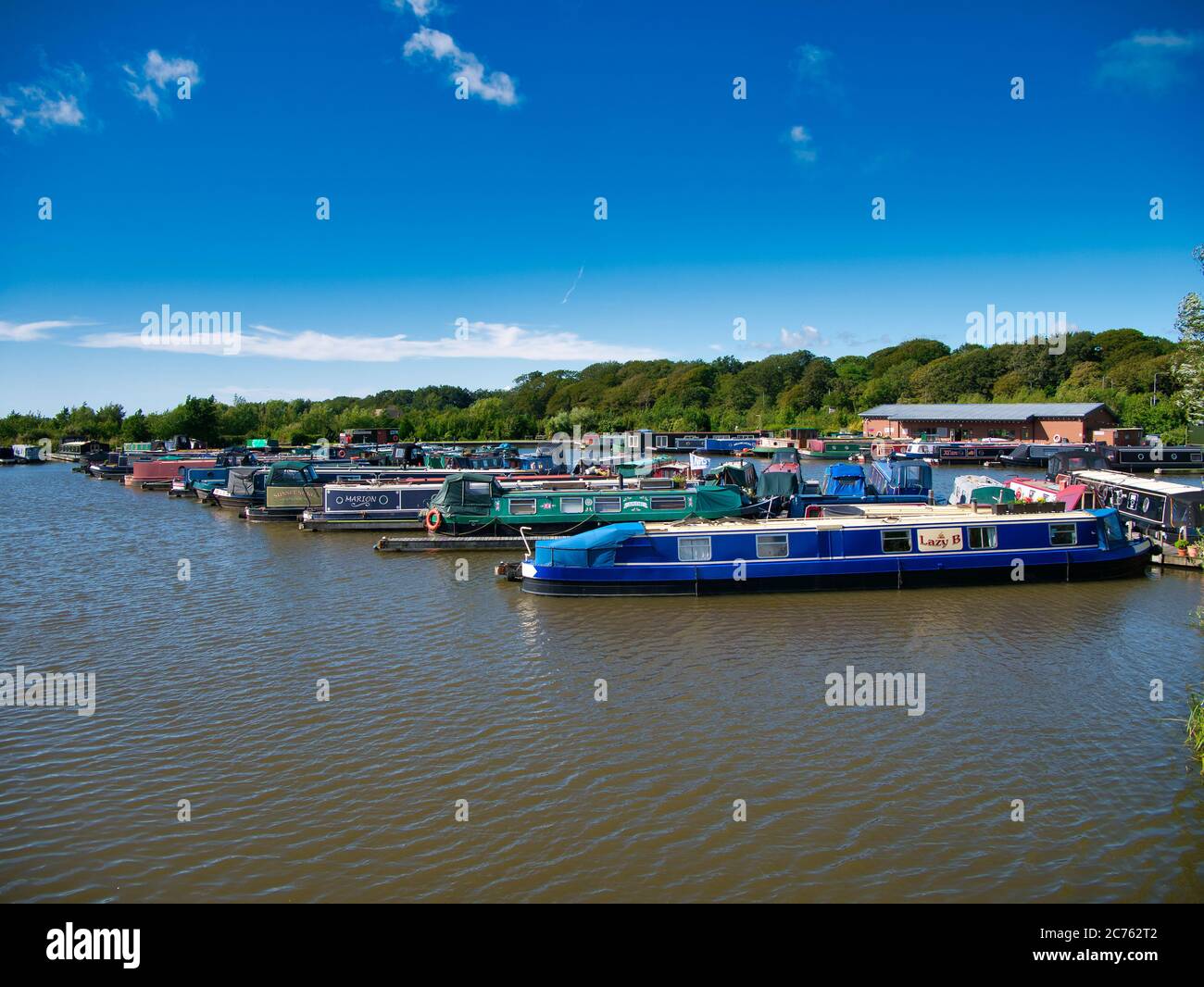 Narrowboats moored at pontoons at Scarisbrick Marina on the Leeds Liverpool Canal in Lancashire in the UK. Taken on a sunny day. Stock Photo