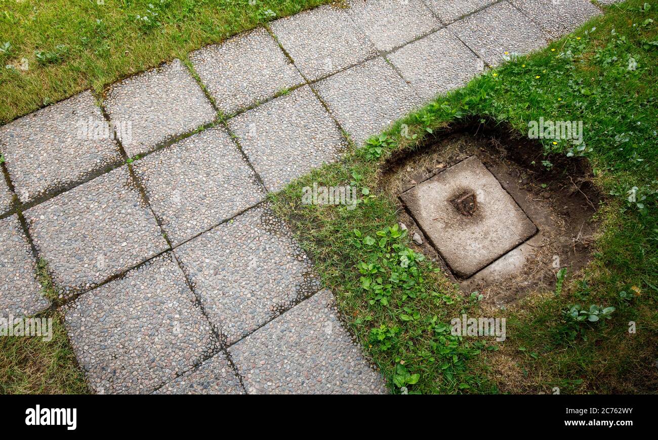 Concrete waste disposal well cover dug out from underneath lawn Stock Photo