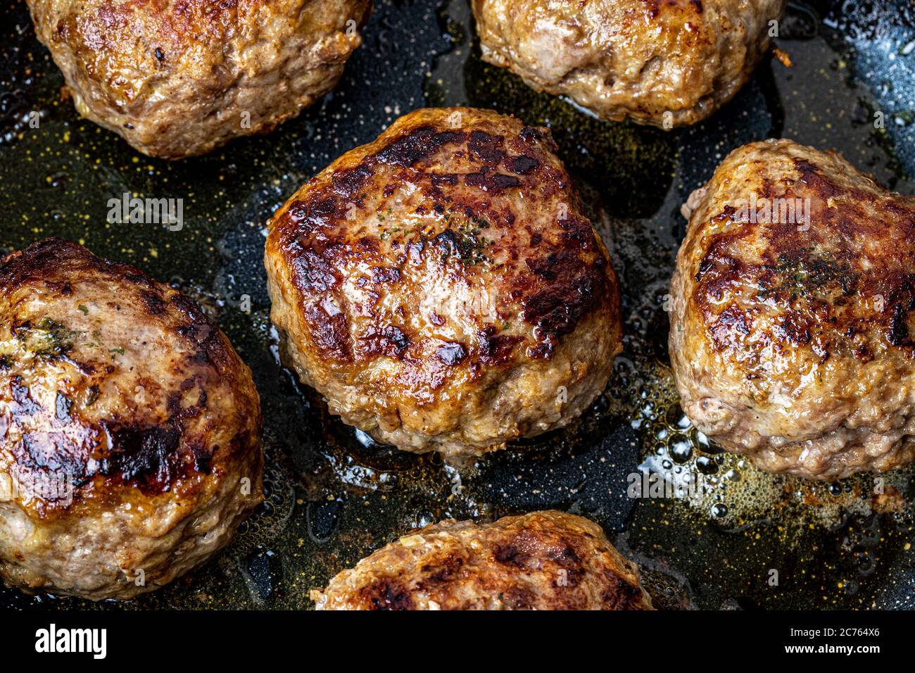 Beef cutlets, heated in a ceramic black skillet with vegetable oil. The