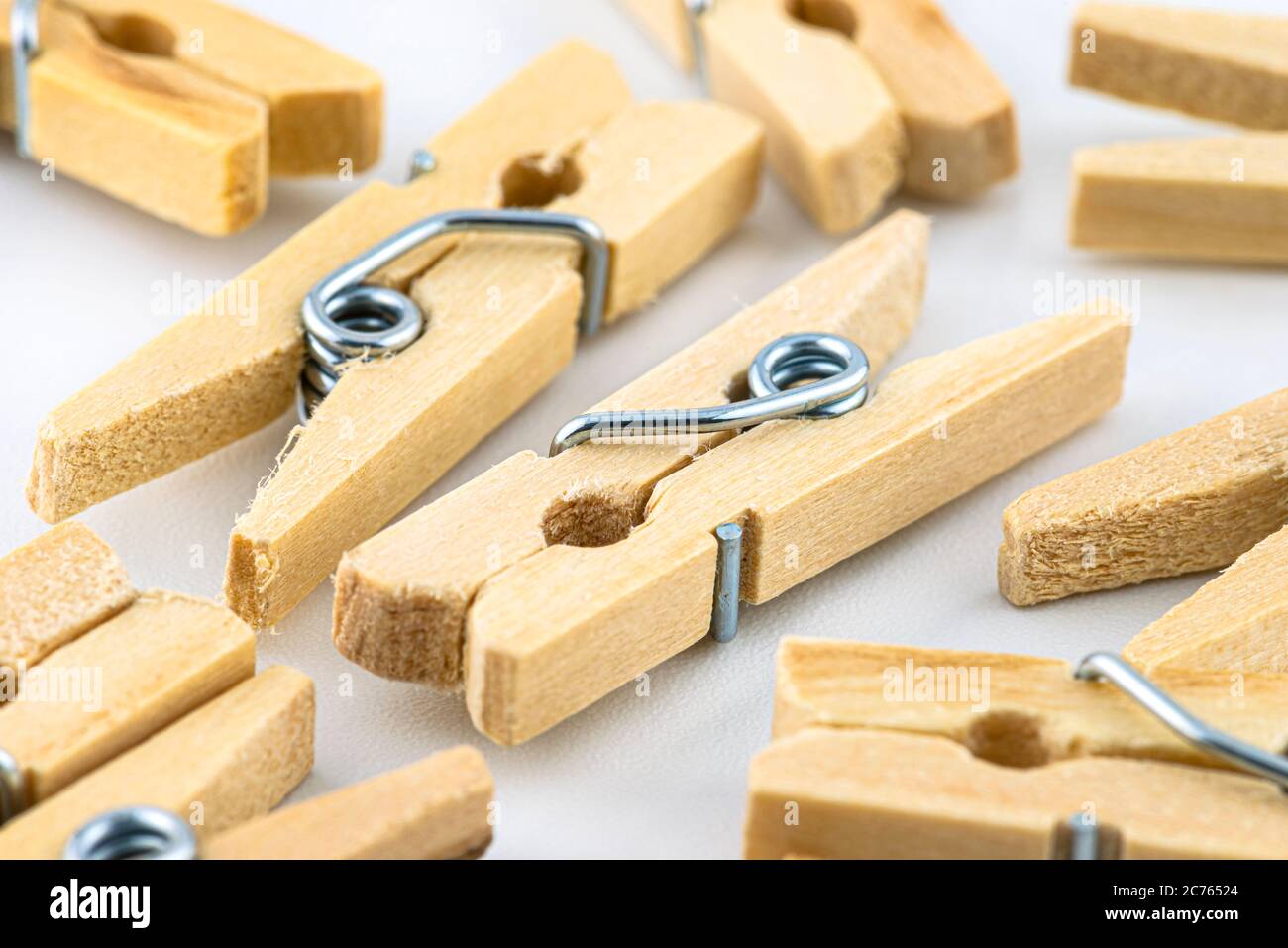 Macro shot of miniature, wooden clamps lying in a group on a white background. Stock Photo