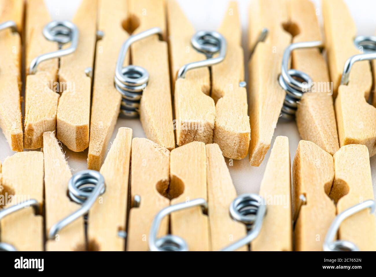 Macro shot of miniature, wooden clamps lying in two rows on a white background. Stock Photo