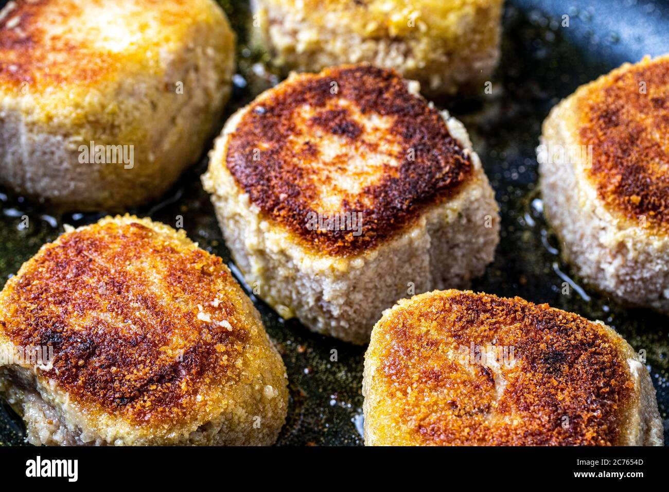 Breaded chicken cutlets, heated in a ceramic black skillet with