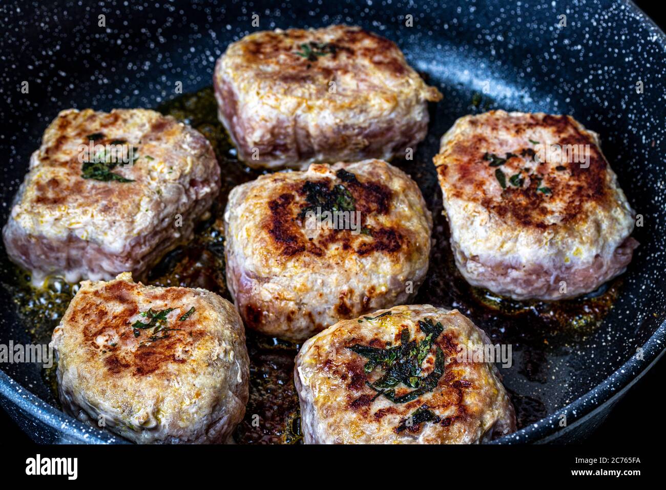 Pork cutlets, heated in a ceramic black skillet with vegetable oil. The