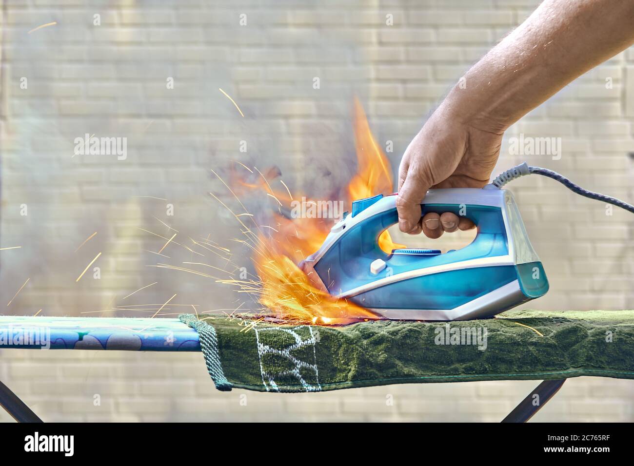 Electrical iron for ironing clothes caused a house fire. The appliance that is forgotten to disconnect from the power is burned. A human hand  is tryi Stock Photo