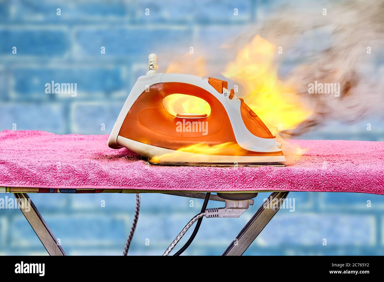 An accident with an ironing iron for clothes, device overheated and caught fire. Ignition of a household electrical appliance at home. Burning propert Stock Photo