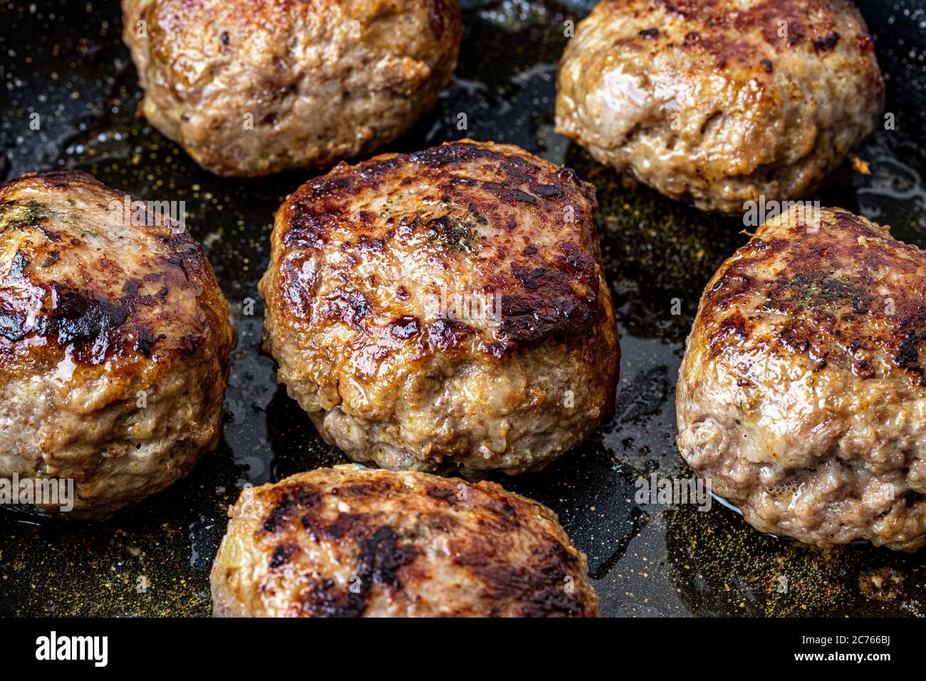Beef cutlets, heated in a ceramic black skillet with vegetable oil. The
