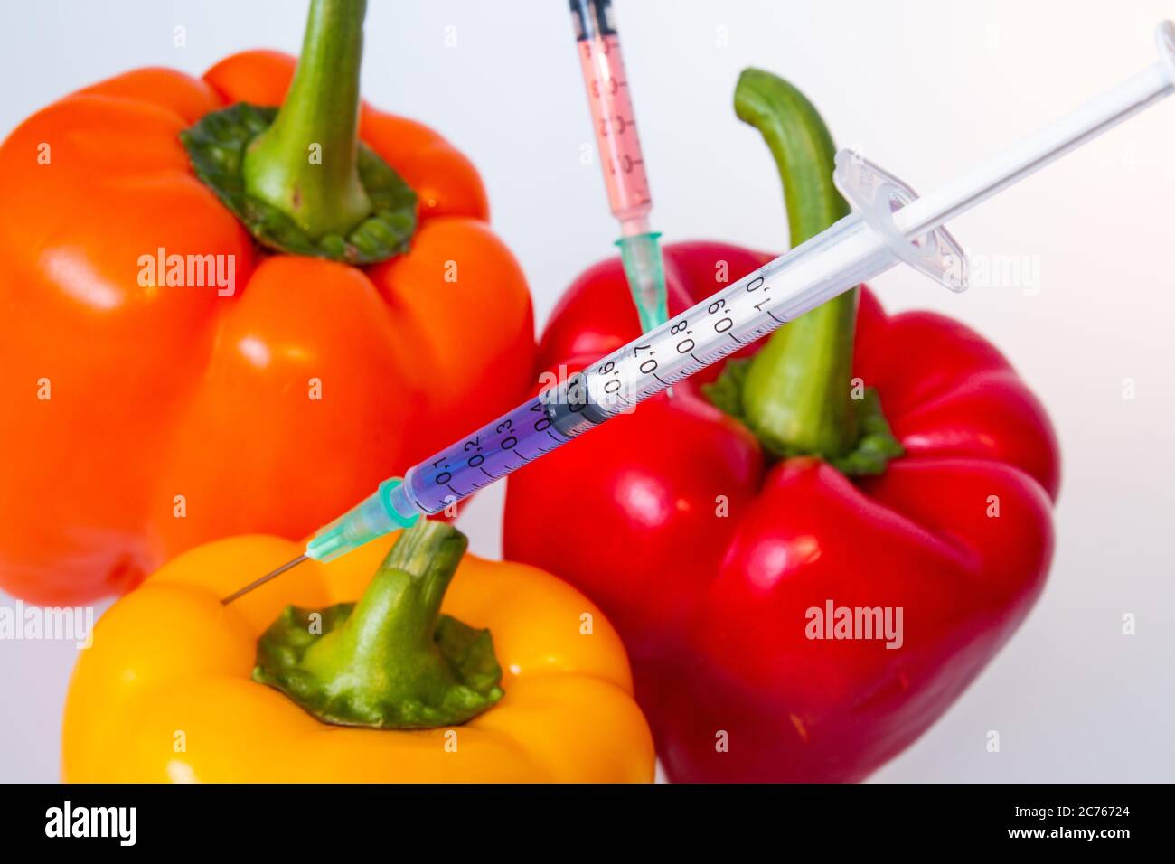 Genetically modified vegetables. GMO food concept. Syringes are stuck in vegetables with chemical additives. Injections into fruits and vegetables. Is Stock Photo