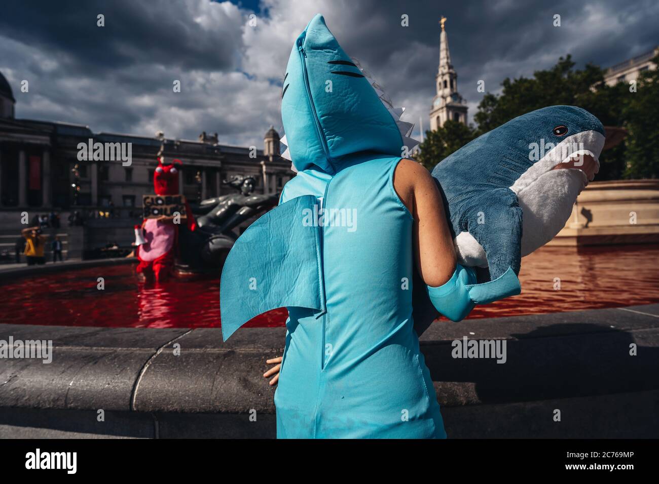 London / UK - 07/11/2020: couple wearing costumes and holding banners standing in the fountain after animal rights group turns fountains water red in Stock Photo