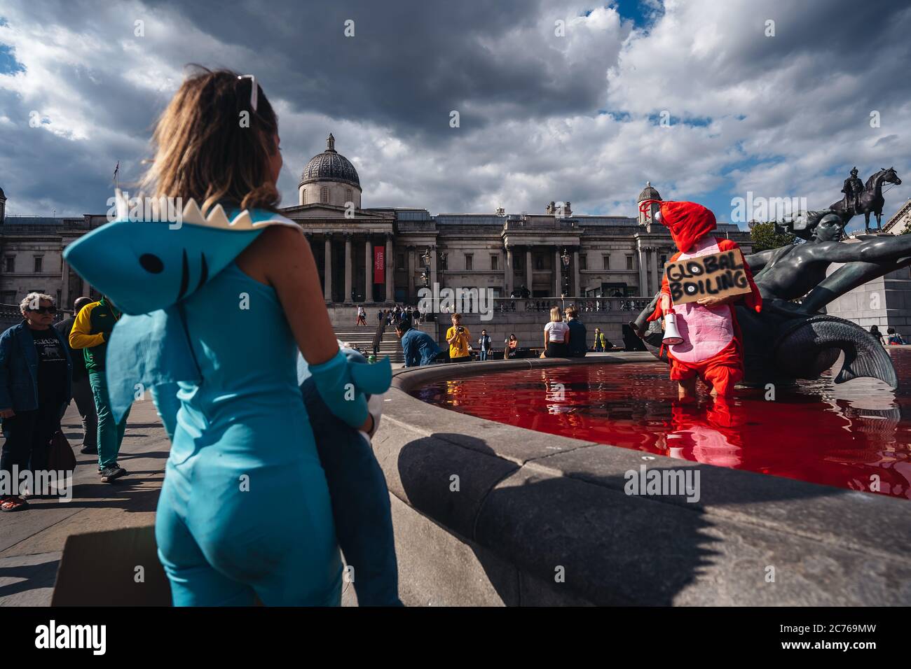 London / UK - 07/11/2020: couple wearing costumes and holding banners standing in the fountain after animal rights group turns fountains water red in Stock Photo