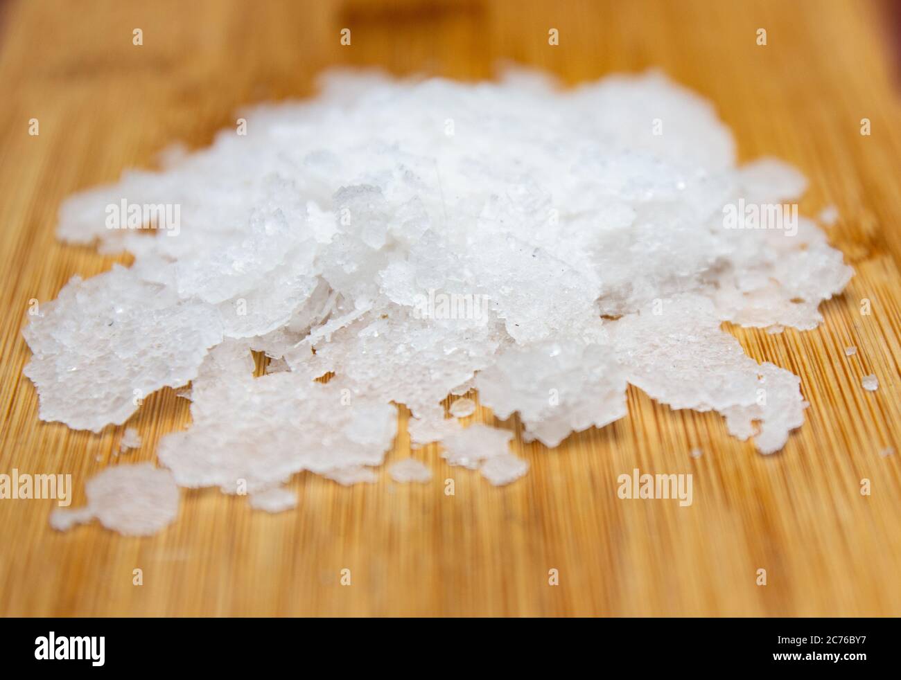 Natural sea salt on wooden background. Anthos sea salt. Flakes of