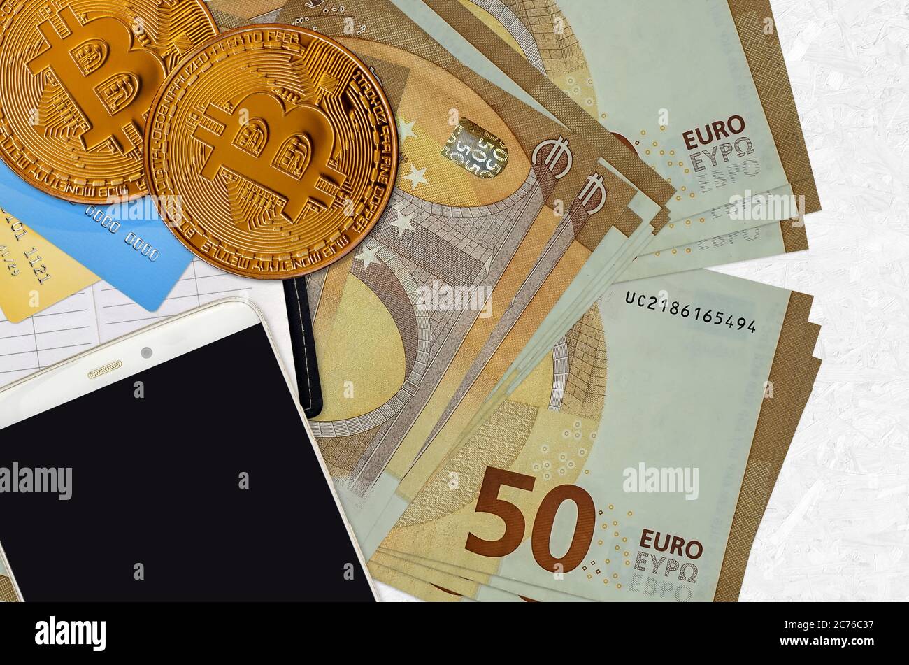 50 euro bills and golden bitcoins with smartphone and credit cards. Cryptocurrency investment concept. Crypto mining or trading transactions Stock Photo