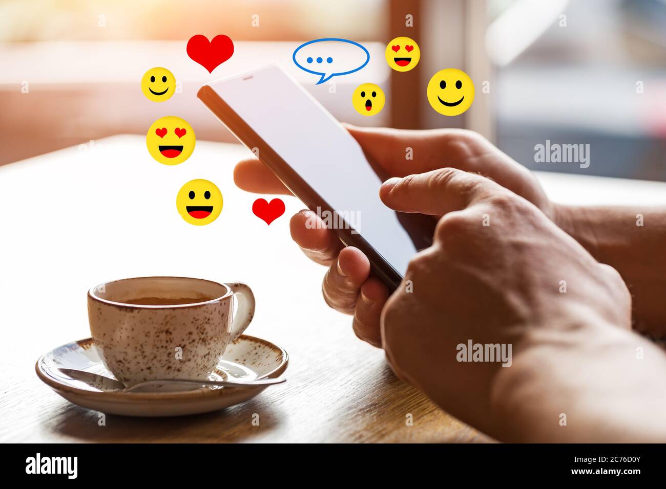 Close up of man's hands holding mobile smart phone with blank copy space screen. Image of man sitting at a table with a coffee in cafe and using mobil Stock Photo
