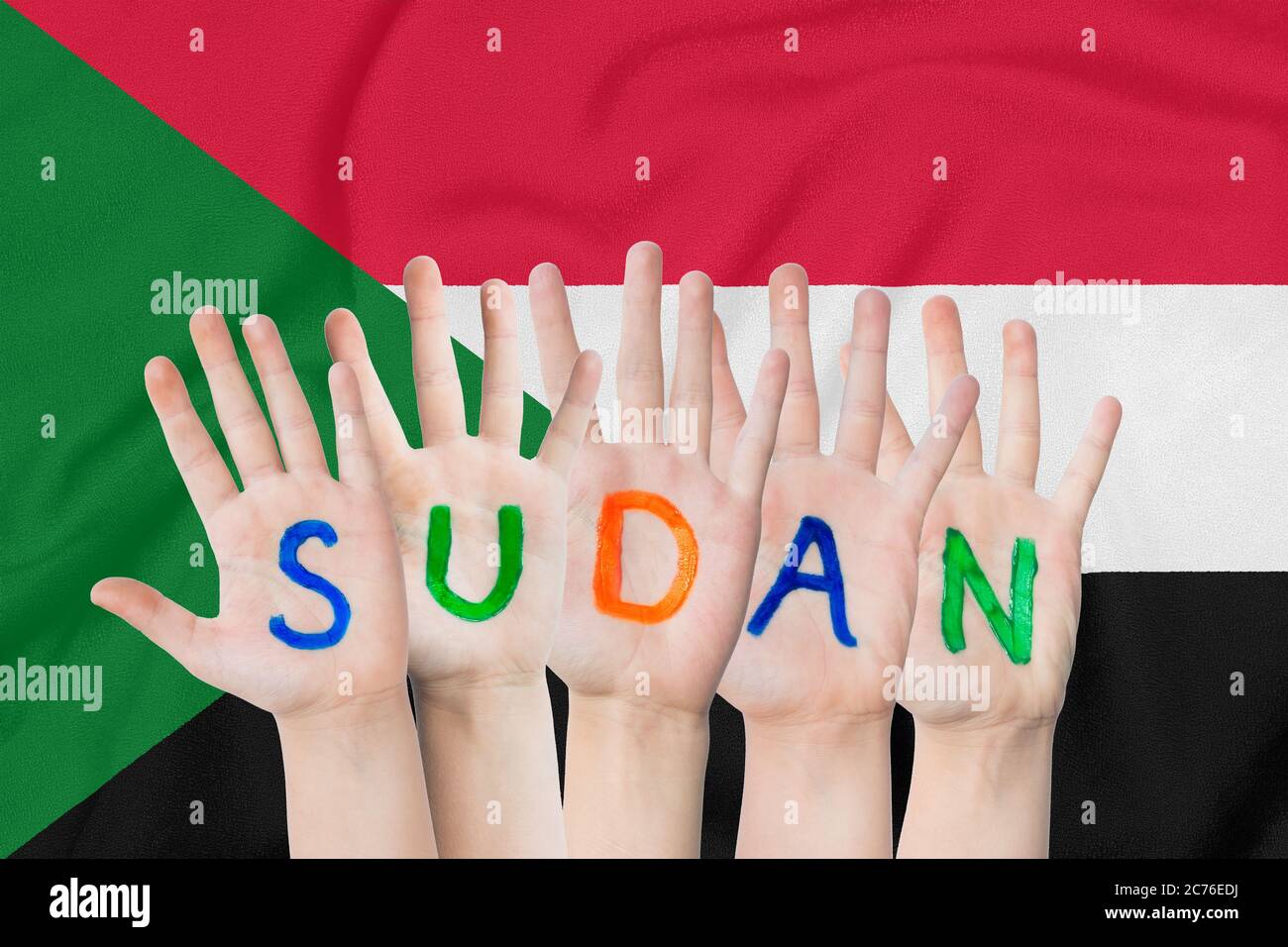 Inscription Sudan on the children's hands against the background of a waving flag of the Sudan Stock Photo