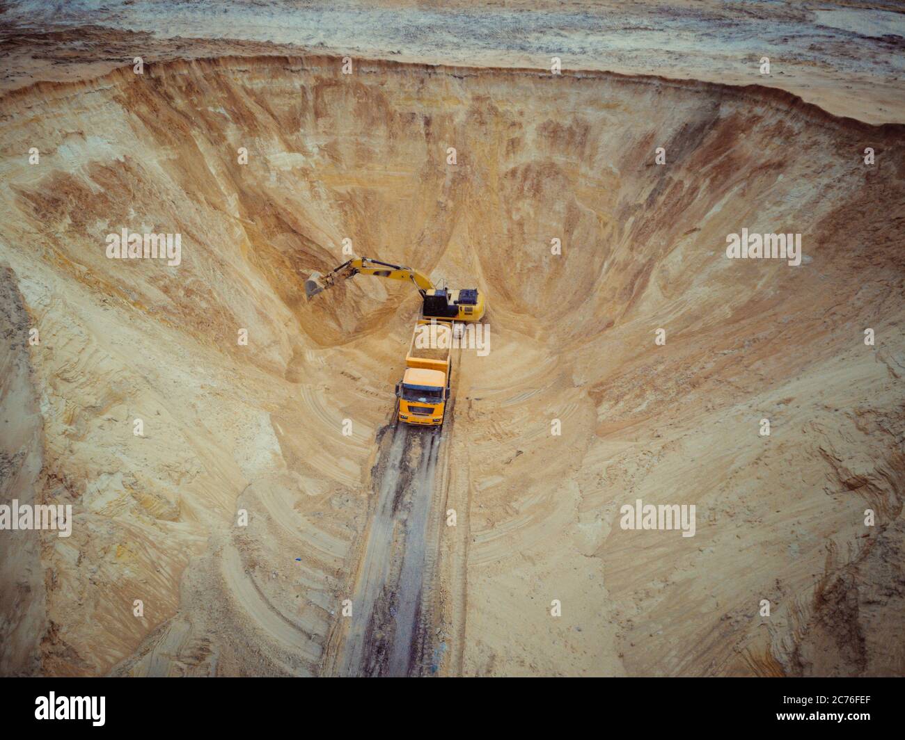 Excavator and dumper truck. Aerial view of loading sand into a truck. A heavy machinery - excavator and truck are working in the sand quarry. Stock Photo