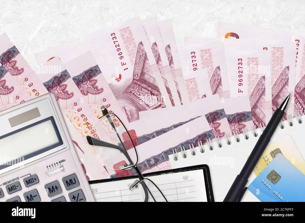 100 Thai Baht bills and calculator with glasses and pen. Tax payment season concept or investment solutions. Financial planning or accountant paperwor Stock Photo