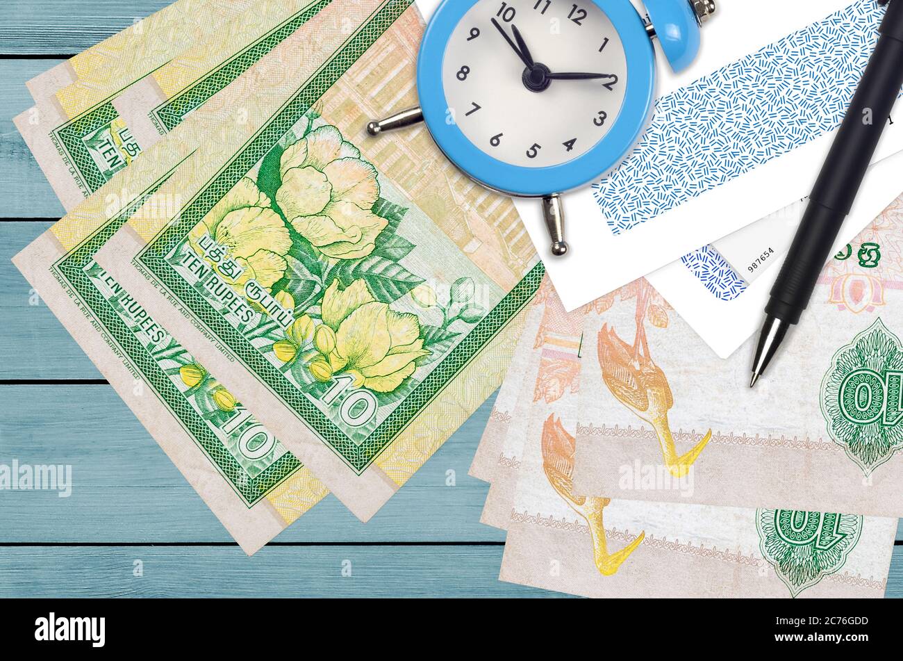 10 Sri Lankan rupees bills and alarm clock with pen and envelopes. Tax