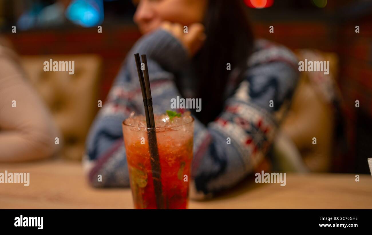 A woman drinks an alcoholic cocktail in a cafe. Close-up of a woman drinking a red cocktail in a cafe. Drinks, people and lifestyle concept-close Stock Photo