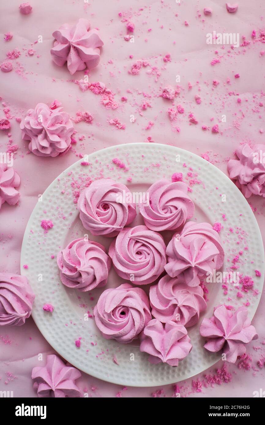 Pink meringues on plate, colorful background, top view Stock Photo