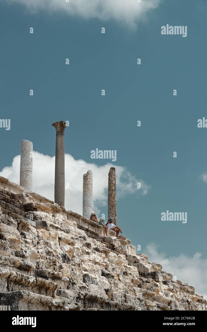 Couple sitting on the top of Ruins in Tyre. People Resting after Excursion along Necropolis in Lebanon. Visiting Famous Place. World Heritage. Active Stock Photo