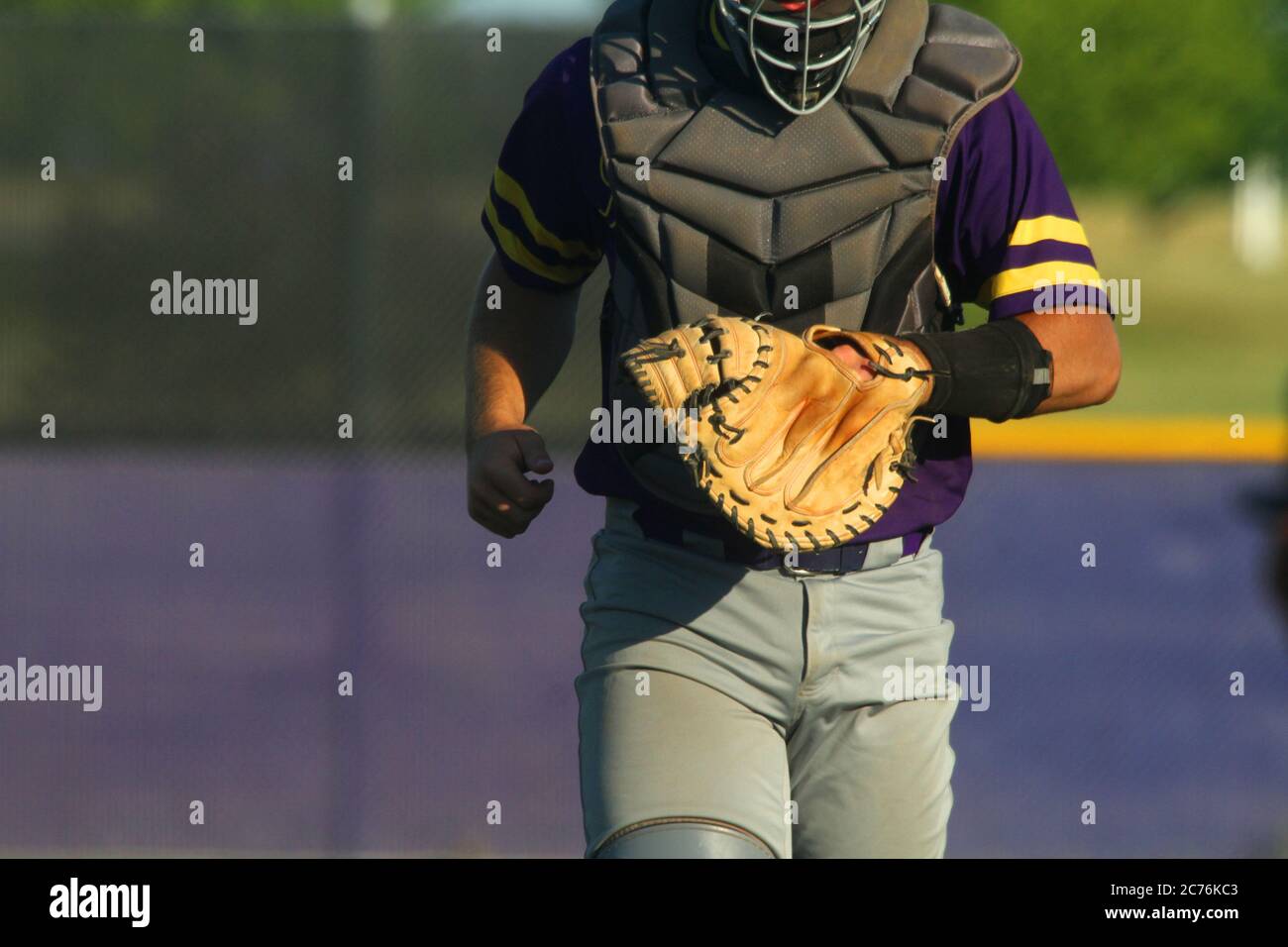 A close-up image of a baseball catcher heading back to home plate following a visit to the pitcher's mound. Stock Photo