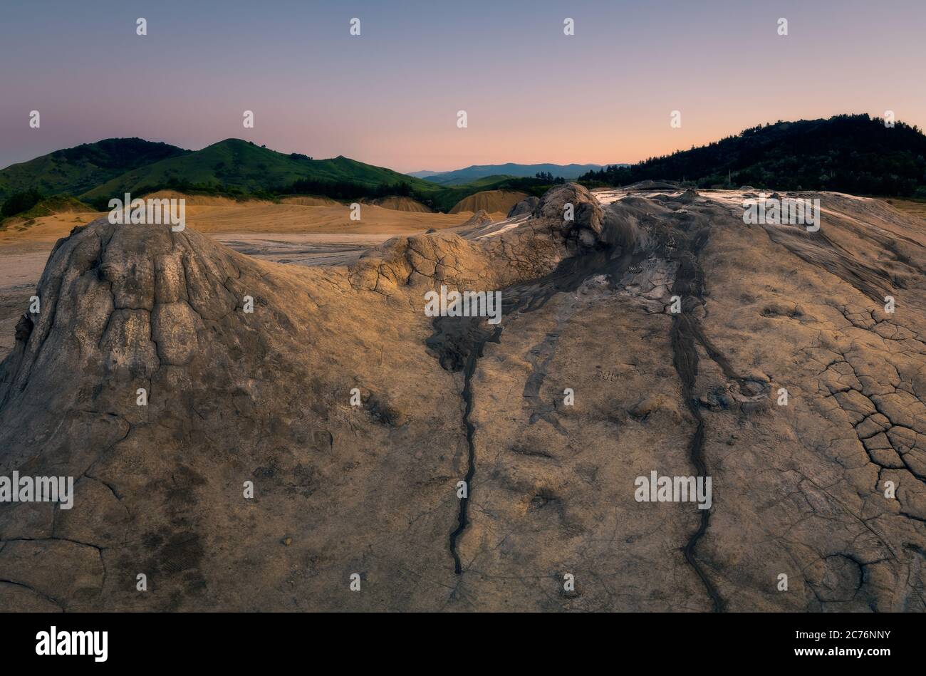Panorama shot of some of the craters at Muddy Volcanoes in Romania, Buzau County with the mountains in the background against a clear sky Stock Photo