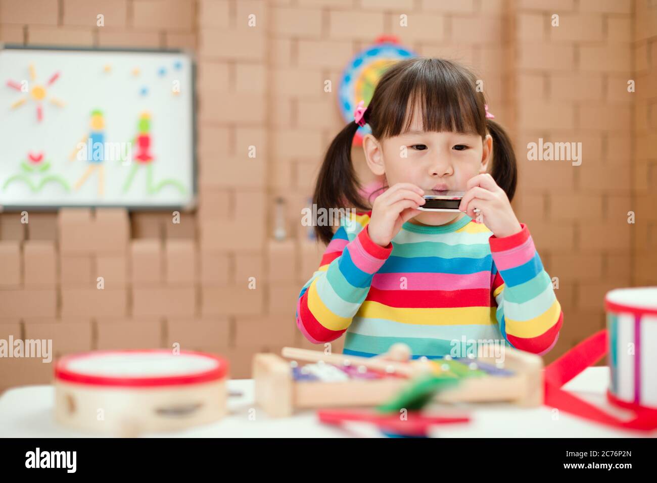 toddler girl play harmonica at home for homeschooling Stock Photo Alamy