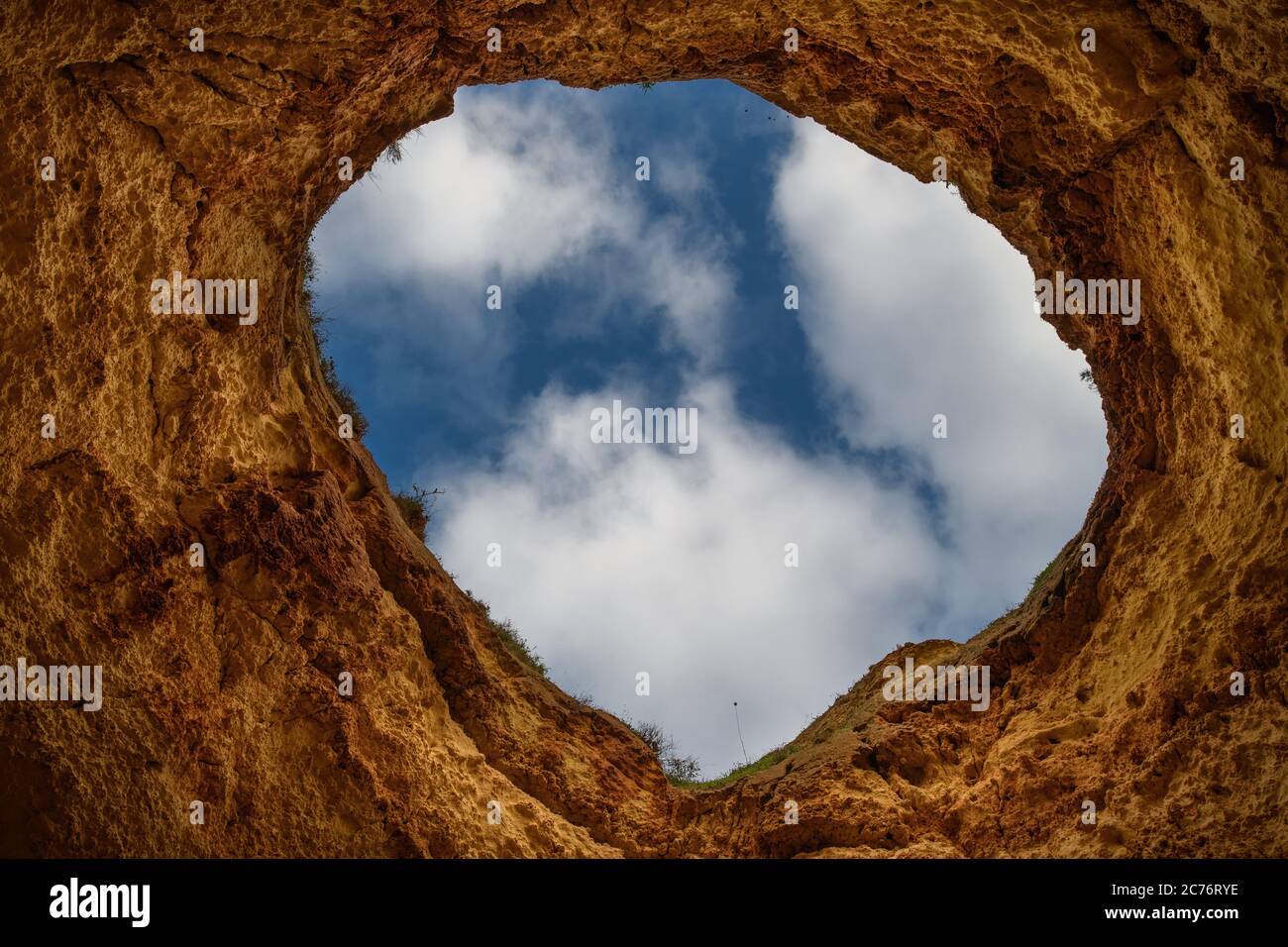 View of a cloudy sky through a hole in rocks, Portugal Stock Photo