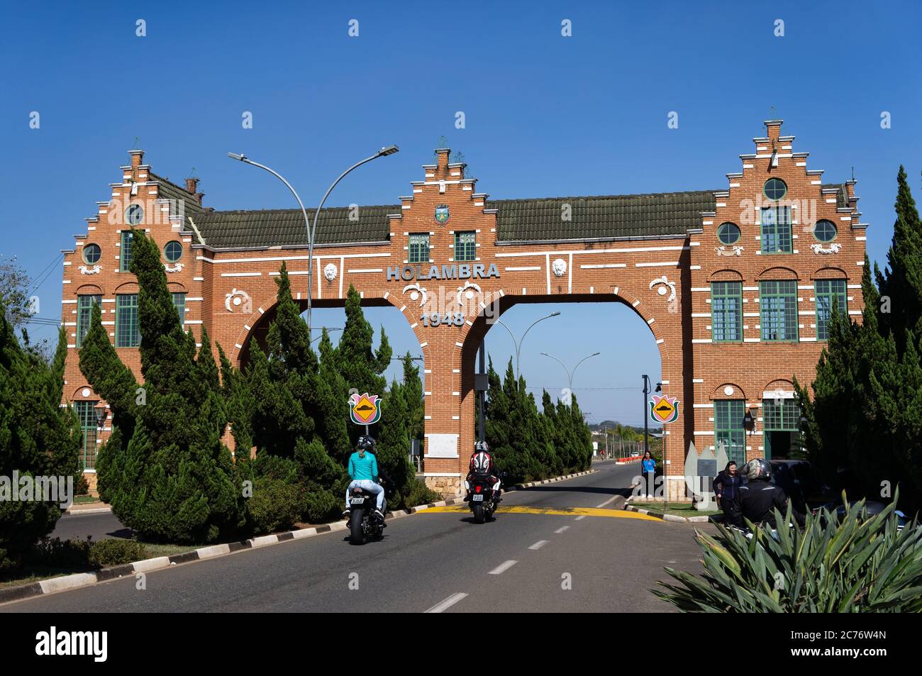 Motorcyclists passing by Holambra city gate entrance bricks facade with his typical dutch architecture located at Rota dos Imigrantes street. Stock Photo