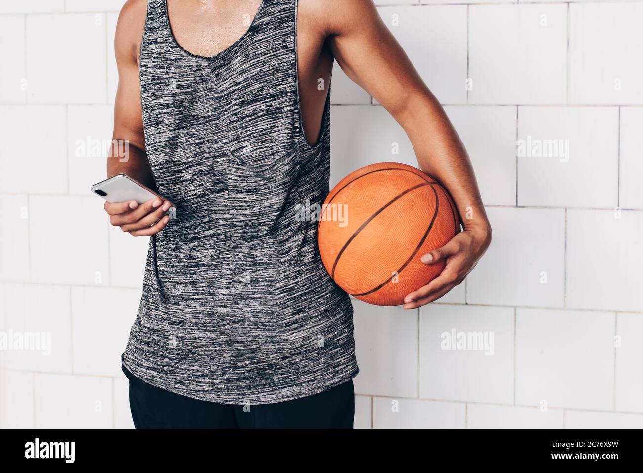 close up of an unrecognizable young man looking at his smartphone while holding a basketball Stock Photo