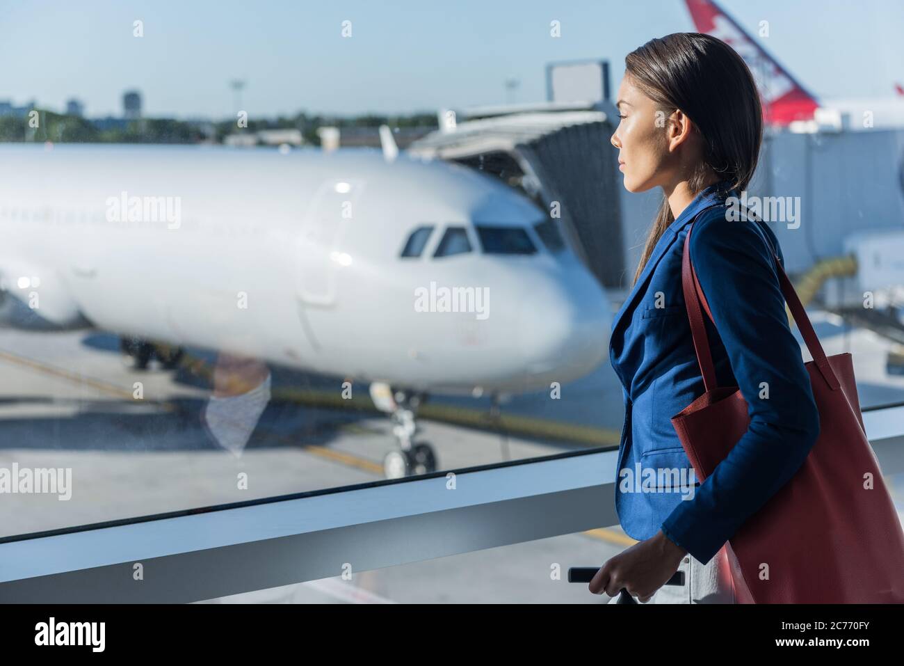 Woman looking at window in airport. Asian tourist relaxing looking at airplanes while waiting at boarding gate before departure. Travel lifestyle Stock Photo