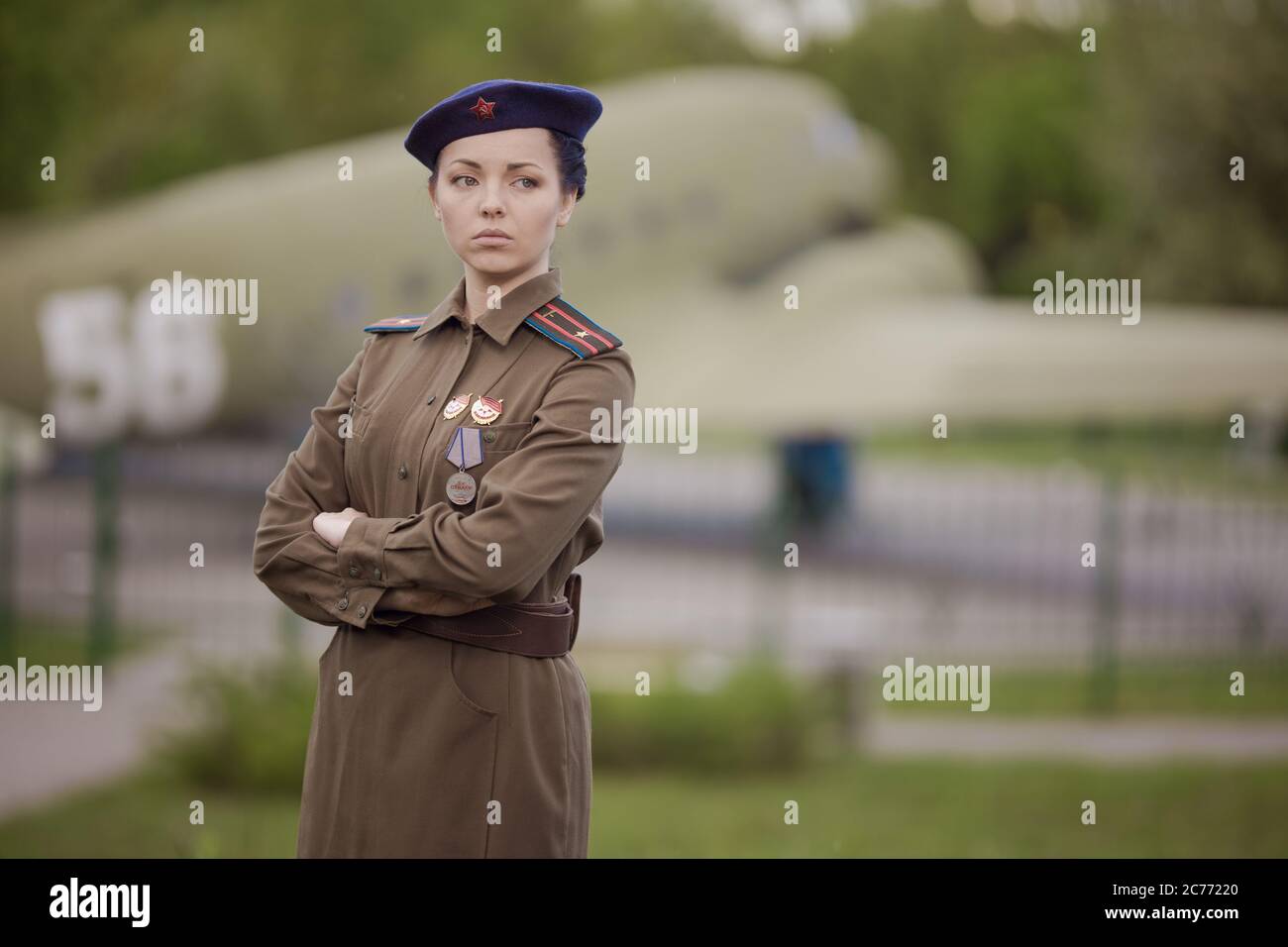 A young female pilot in uniform of Soviet Army pilots during the World War II. Military shirt with shoulder straps of a major and a beret. Against the Stock Photo