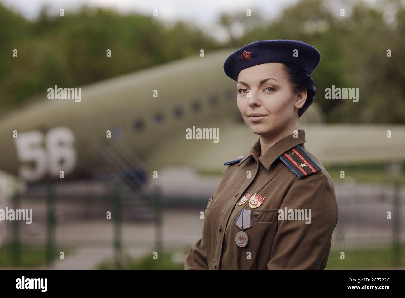 A young female pilot in uniform of Soviet Army pilots during the World War II. Military shirt with shoulder straps of a major and a beret. Against the Stock Photo