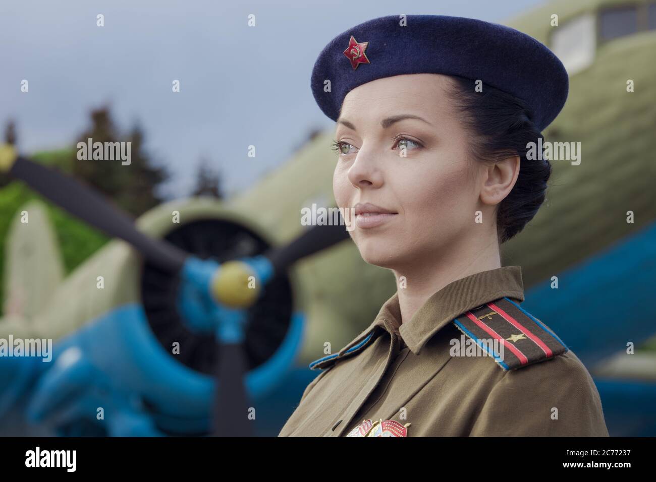 A young female pilot in uniform of Soviet Army pilots during the World War II. Military shirt with shoulder straps of a major and a beret. Against the Stock Photo