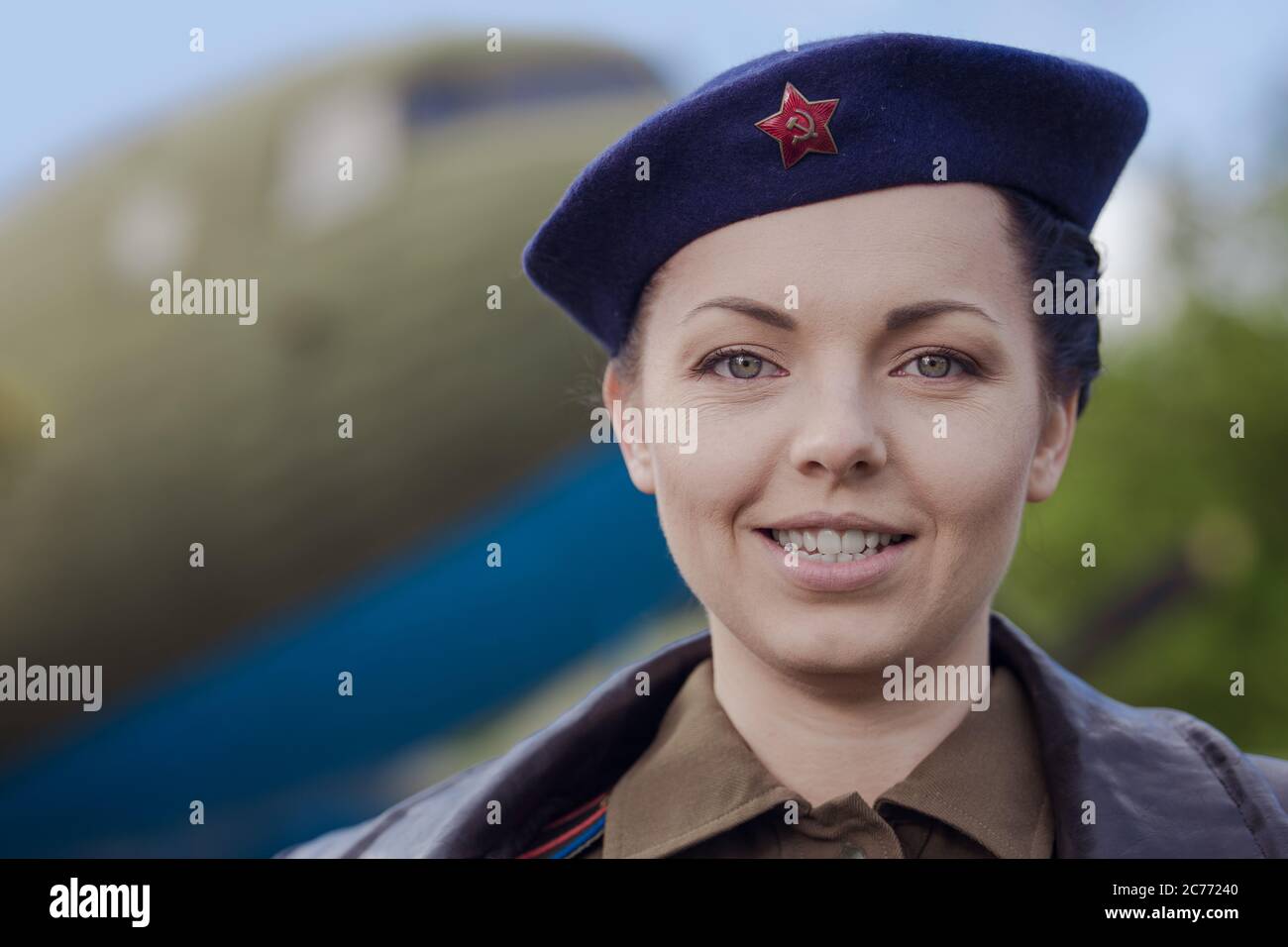 A young female pilot in uniform of Soviet Army pilots during the World War II. Military shirt with shoulder straps of a major and a beret. Against the Stock Photo