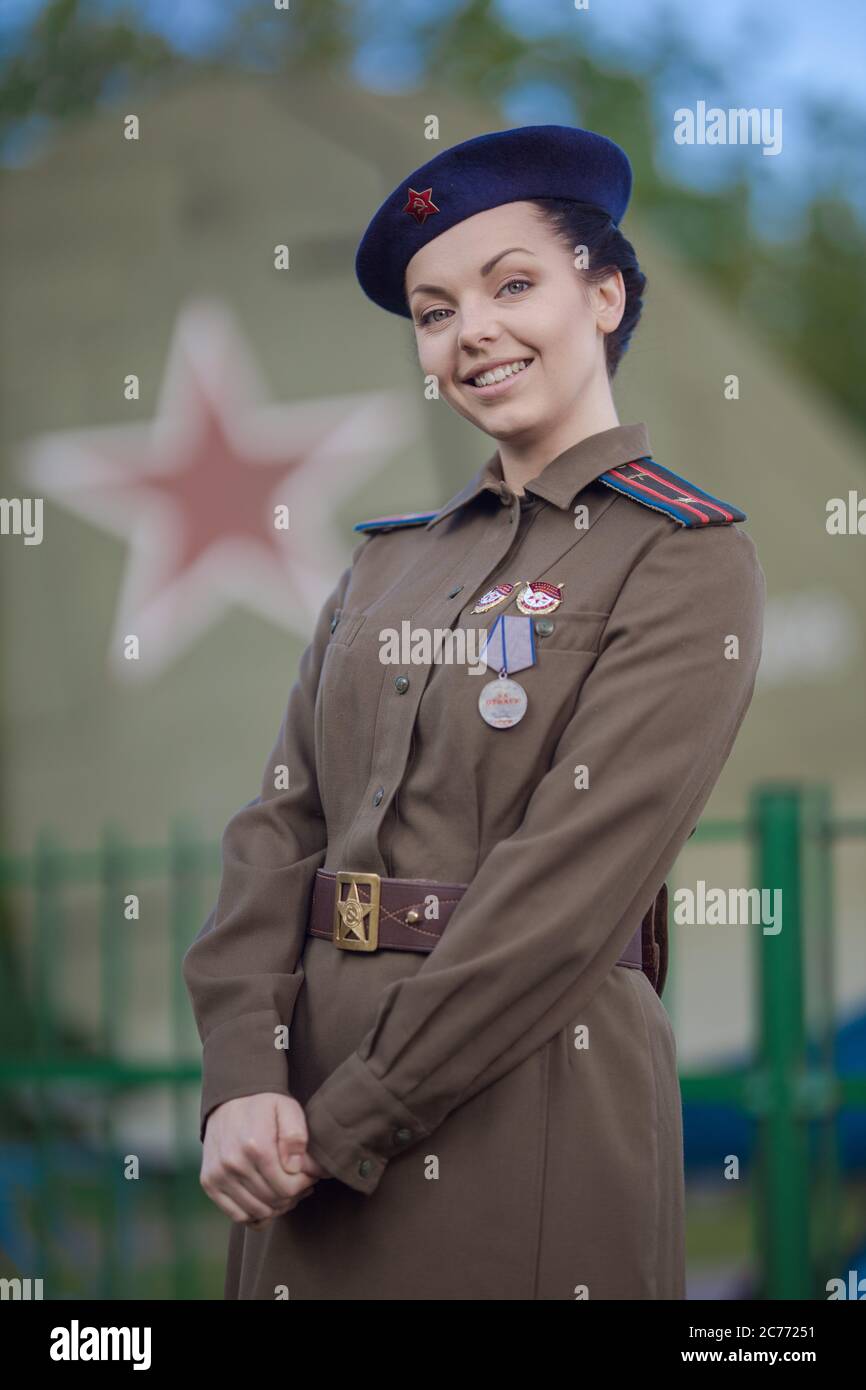 A young female pilot in uniform of Soviet Army pilots during the World War II. Military shirt with shoulder straps of a major and a beret. Against the Stock Photo