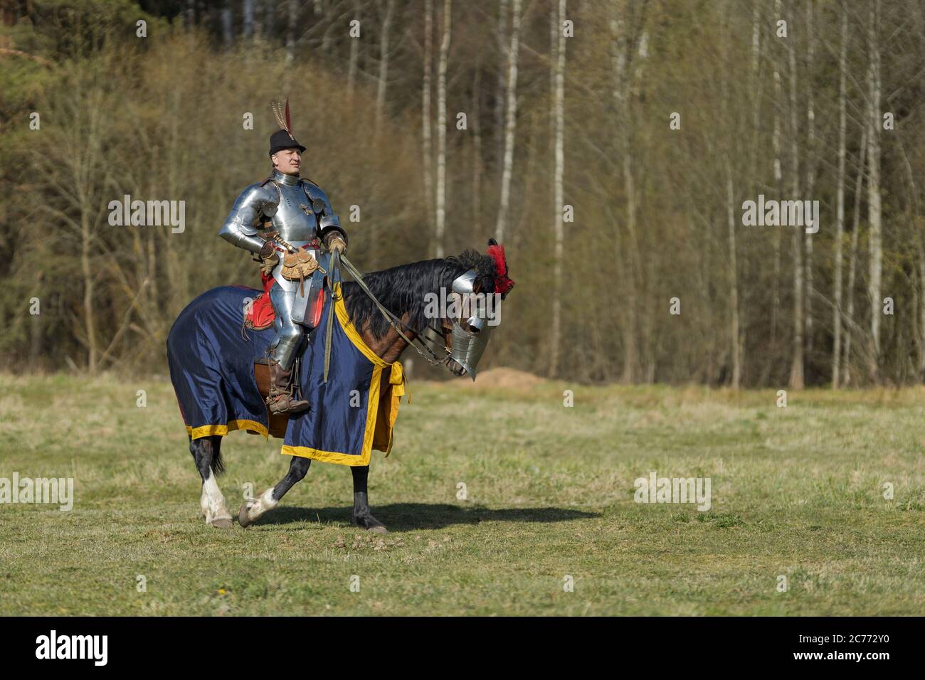 adult man in ancient knight armor rides across the field on a horse in ...