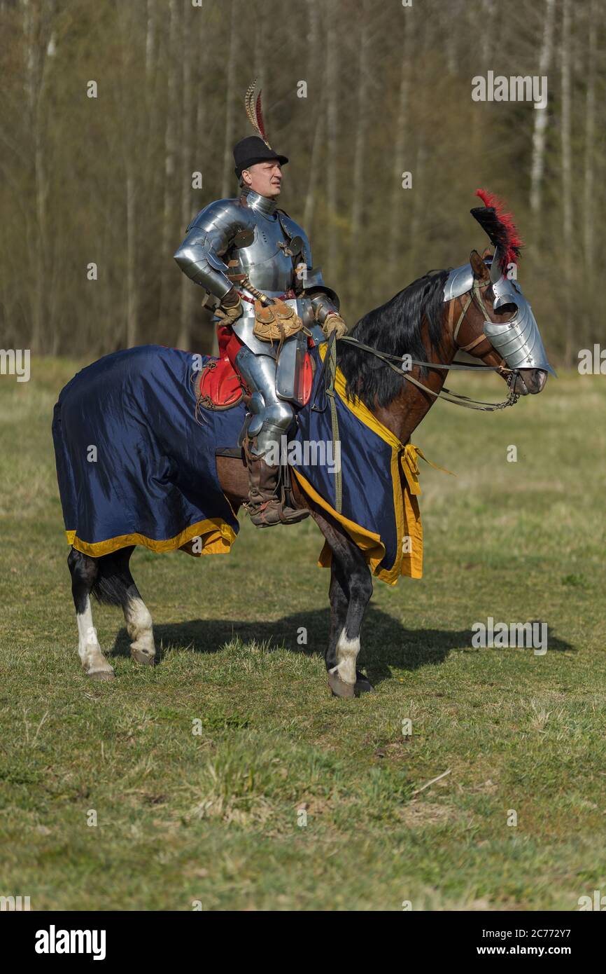 adult man in ancient knight armor rides across the field on a horse in ...