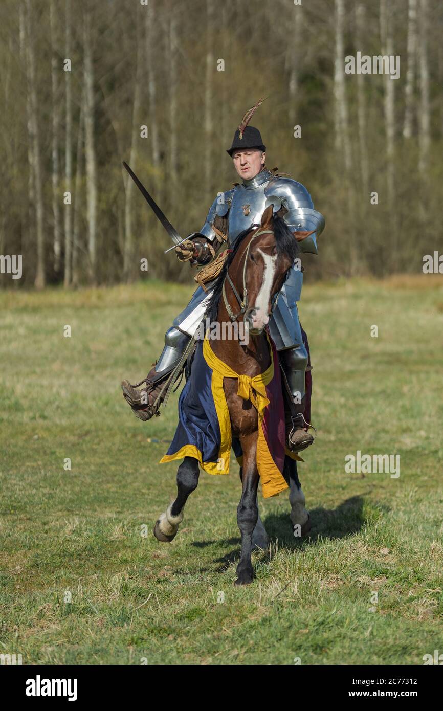 adult man in ancient knight armor rides across the field on a horse in ...