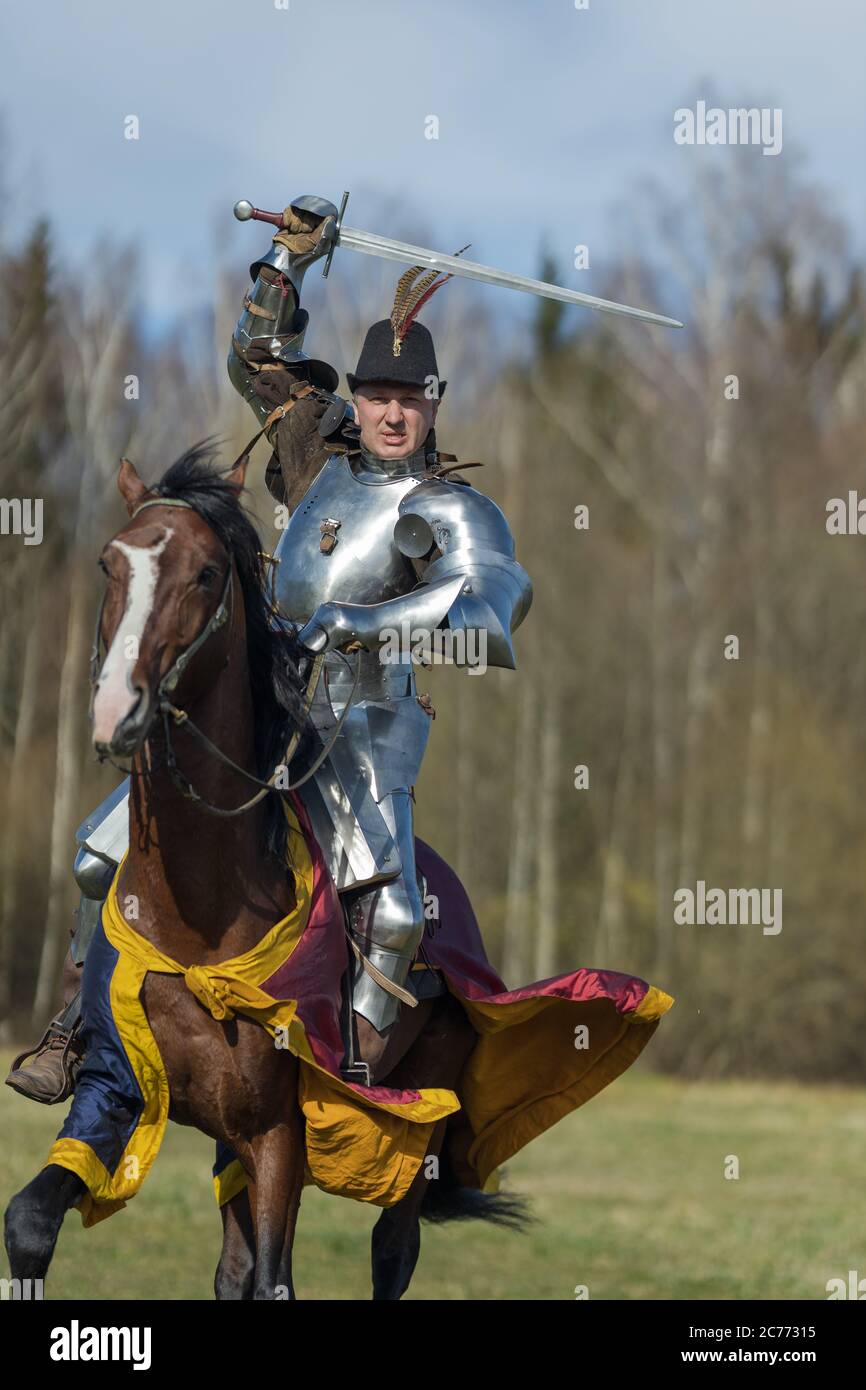 adult man in ancient knight armor rides across the field on a horse in ...