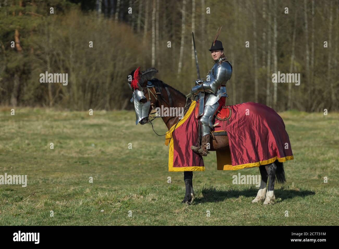 adult man in ancient knight armor rides across the field on a horse in ...